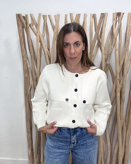Chaqueta de punto marfil con botones negros, de frente con vaquero