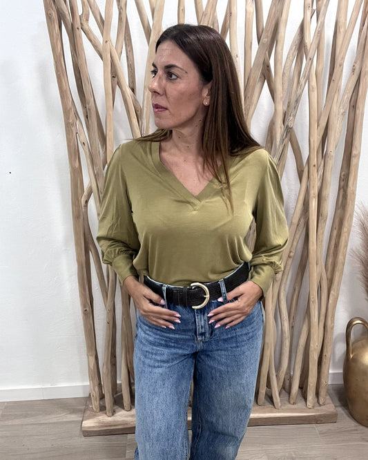 Blusa de punto modal verde oliva con cuello de pico y manga abullonada, de frente con vaquero y cinturón